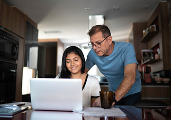 father and daughter looking at laptop screen